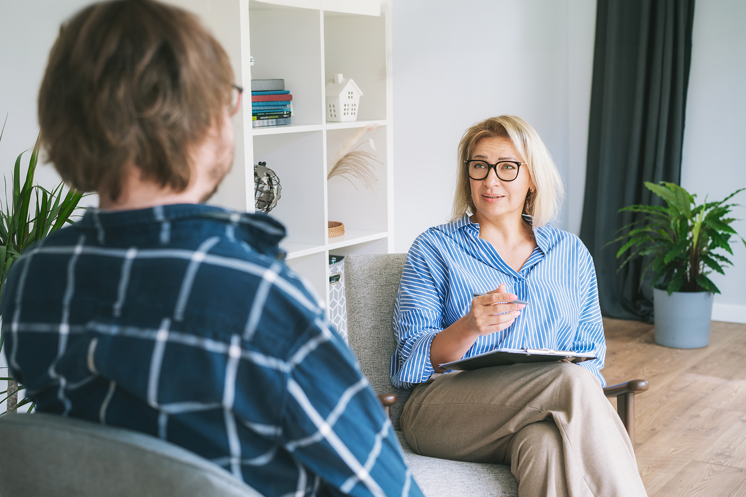 Professional psychotherapy. Female psychologist having session with male patient at mental health clinic, Taking Note During Appointment In Office. Psychological help service. Treatment of depression Professional psychotherapy. Female psychologist having session with male patient at mental health clinic, Taking Note During Appointment In Office. Psychological help service. Treatment of depression